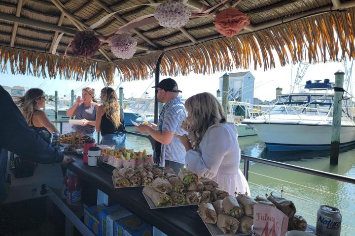 a group of people standing around a table full of food