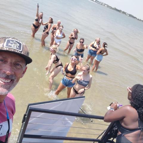 A group of people in swimwear are enjoying a sunny day at the beach, standing in shallow water.